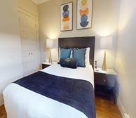 Signal Hill Gate - Short-term rental in St. John's primary bedroom with queen bed and blue accent pillows - Premiere Suites