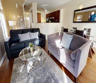 Beechwood - Furnished apartment in Ottawa living room with black couch and grey couch and glass coffee table - Premiere Suites