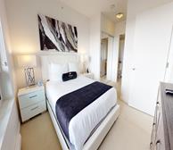 Metro Place - Burnaby fully furnished apartment primary bedroom with queen bed and Premiere Suites pillow