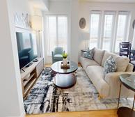 Assomption - Moncton furnished short-term rental spacious living room with cream couch and tv unit - Premiere Suites