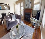 Beechwood - Ottawa fully furnished apartment living room with grey couch and stone fireplace - Premiere Suites