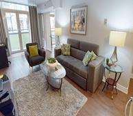 The Greystones - Halifax fully furnished apartment living room with grey couch and grey armchair and balcony access - Premiere Suites