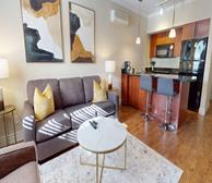 Signal Hill Gate - Fully furnished apartment in St. John's living room with grey couch and yellow pillows - Premiere Suites