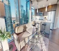 Encore Tower - Edmonton fully furnished apartment kitchen and living room with grey cabinets and grey barstools - Premiere Suites