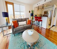 Bishops Landing LW79 - Halifax fully furnished apartment kitchen and living room with grey couch and orange accents - Premiere Suites