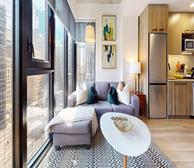 The Emmy - Open-concept living area in a short-term rental in Ottawa with grey sectional - Premiere Suites